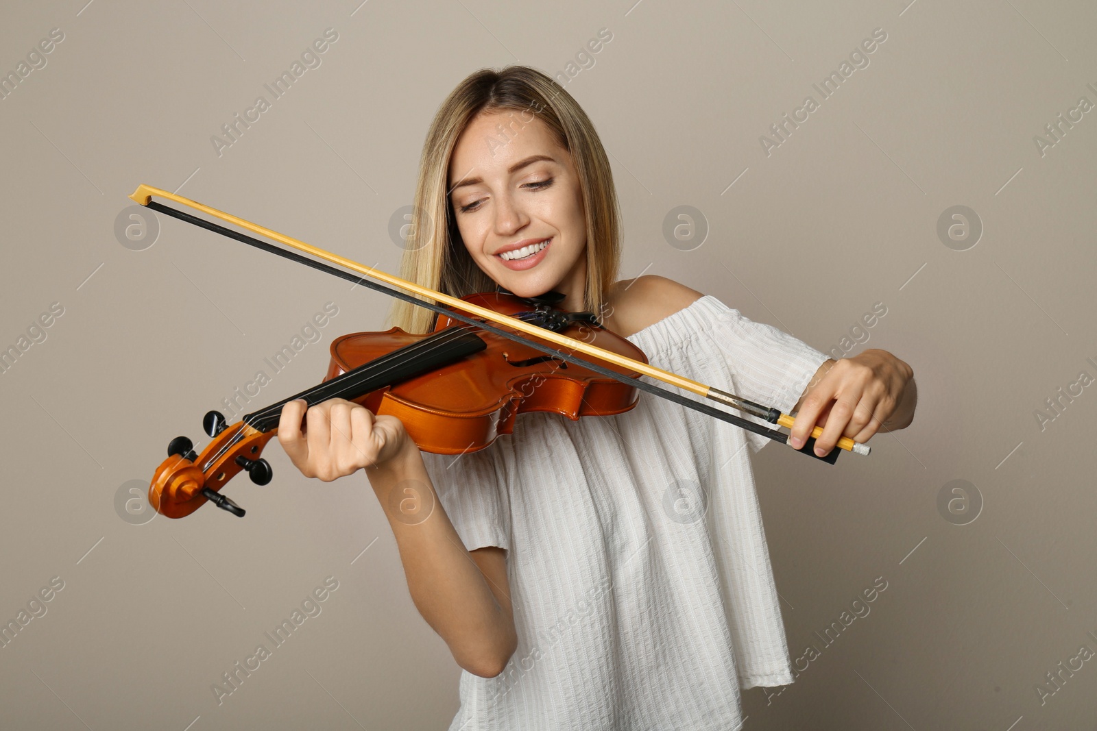 Photo of Beautiful woman playing violin on beige background