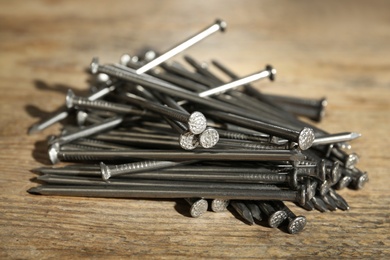 Photo of Pile of metal nails on wooden background