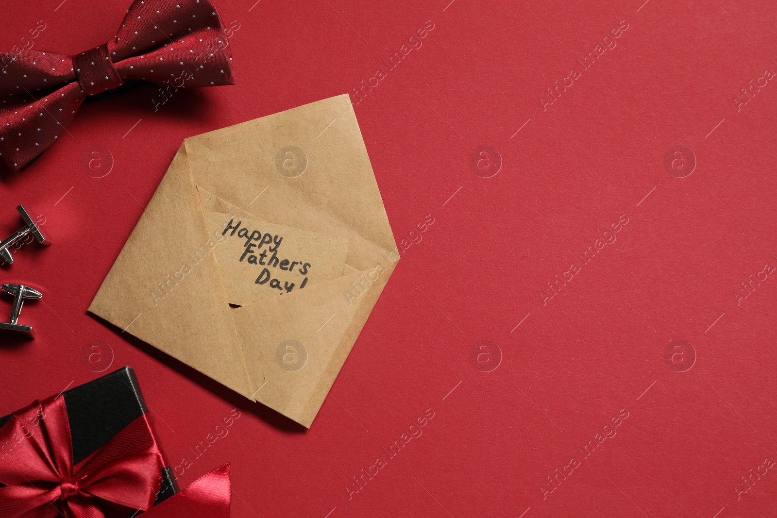 Photo of Card with phrase Happy Father's Day, gift box and men accessories on red background, flat lay. Space for text