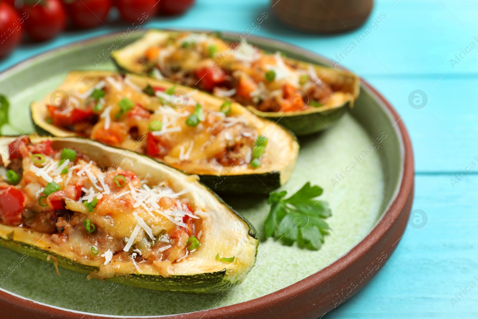 Photo of Delicious stuffed zucchini served on light blue wooden table, closeup