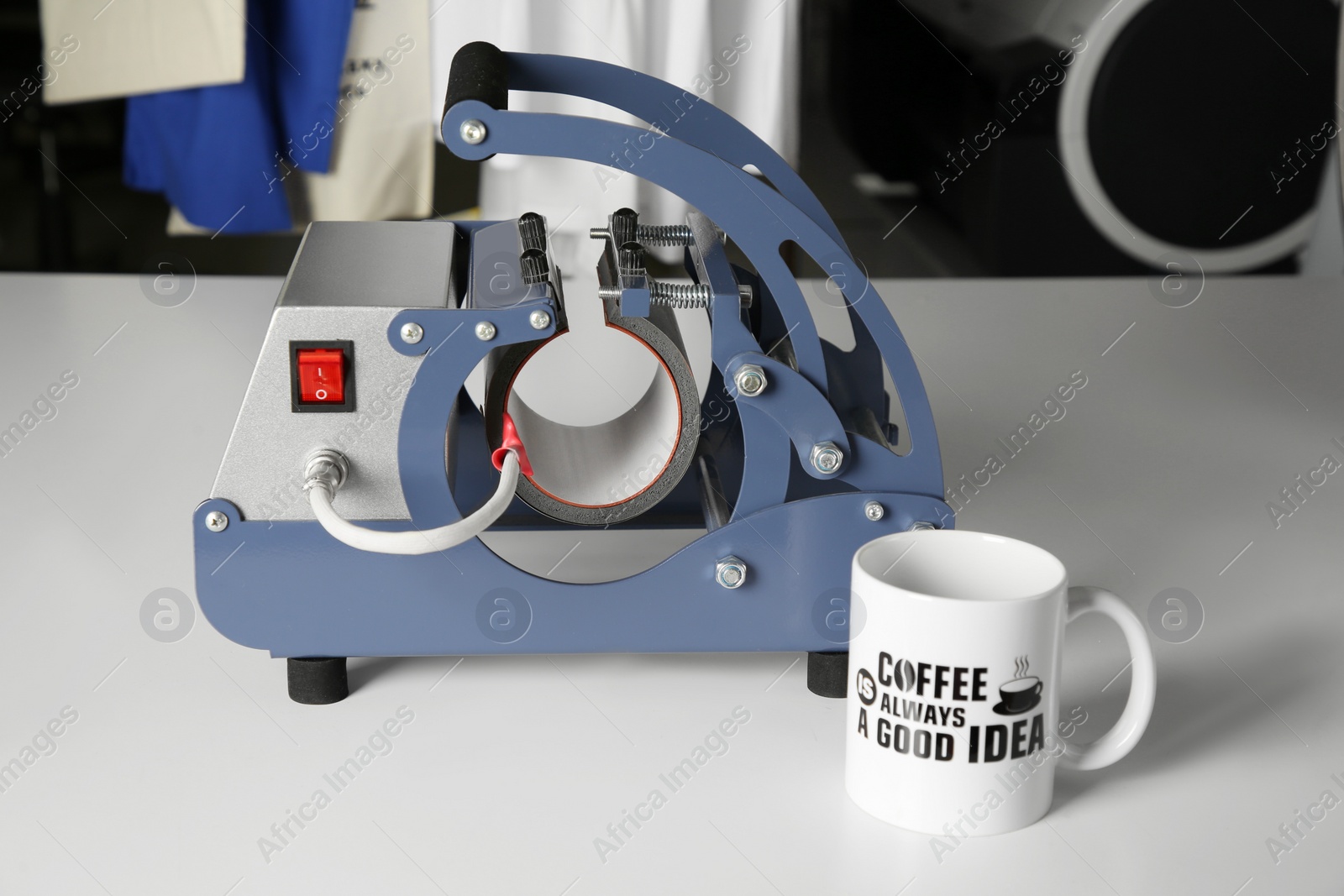 Photo of Printing logo. Heat press and cup on white table