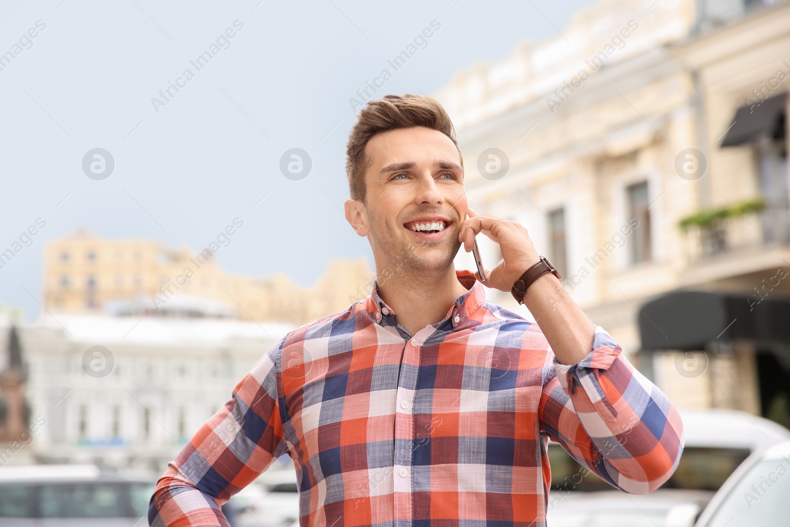 Photo of Attractive young man talking on phone outdoors