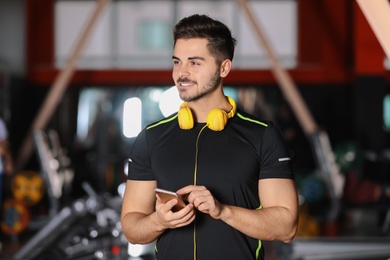 Young man with headphones and mobile device at gym