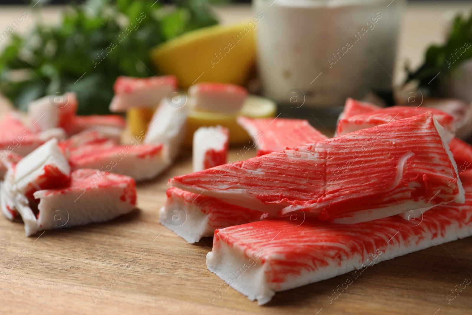 Photo of Delicious crab sticks on wooden board, closeup