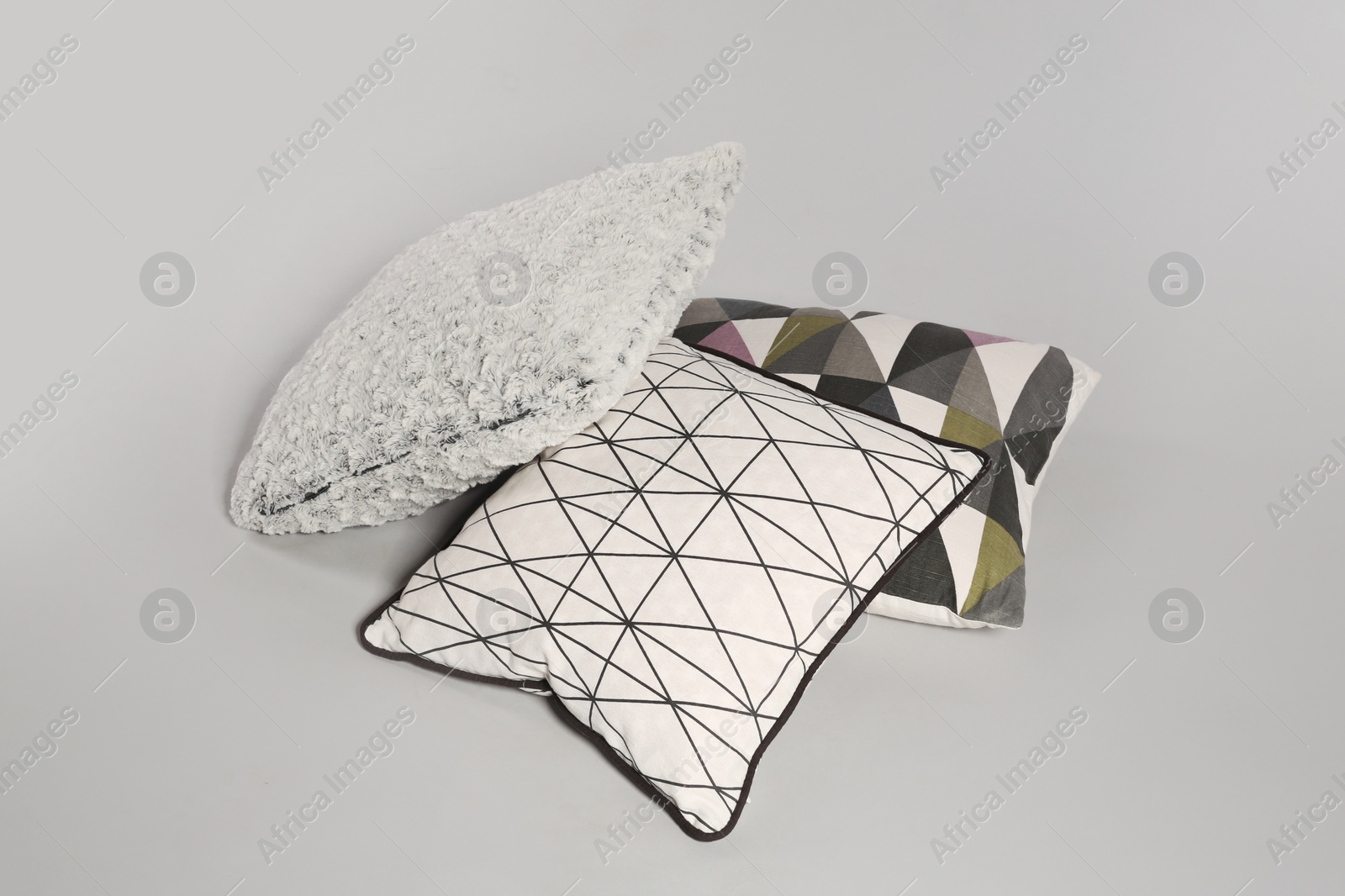 Photo of Pile of stylish decorative pillows on light background