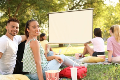 Young couple with popcorn watching movie in open air cinema. Space for text