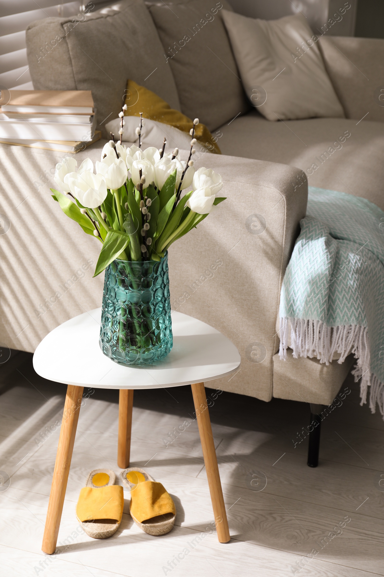 Photo of Beautiful bouquet of willow branches and tulips in vase on table indoors