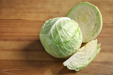 Photo of Whole and sliced cabbages on wooden table