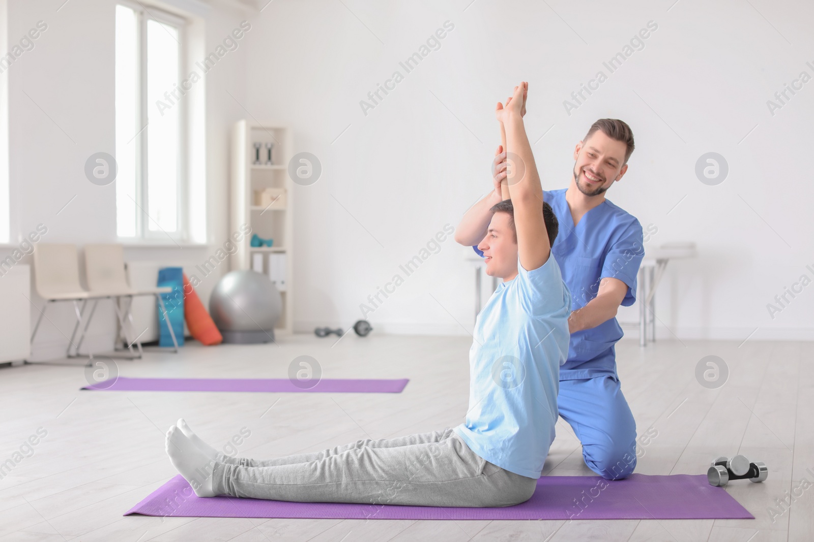 Photo of Physiotherapist working with male patient in clinic