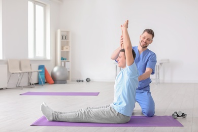 Photo of Physiotherapist working with male patient in clinic