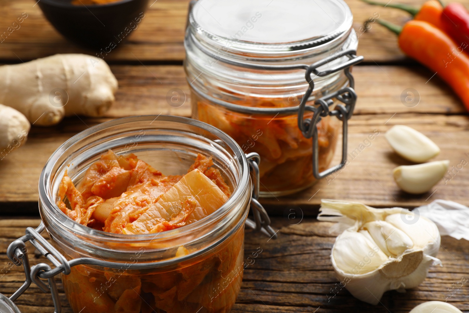 Photo of Delicious kimchi with Chinese cabbage and ingredients on wooden table, closeup