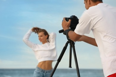 Photographer taking picture of model with professional camera near sea