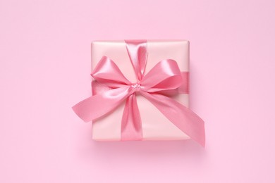 Beautiful gift box with bow on pink background, top view