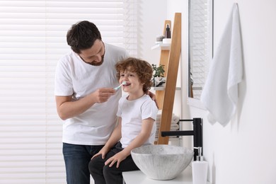 Father helping his son to brush teeth in bathroom