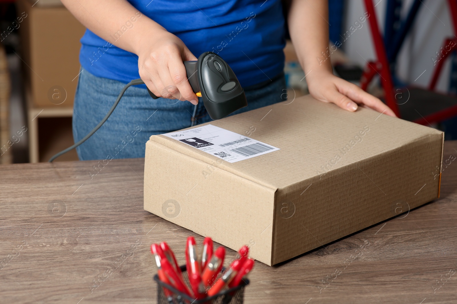 Photo of Post office worker with scanner reading parcel barcode at counter, closeup