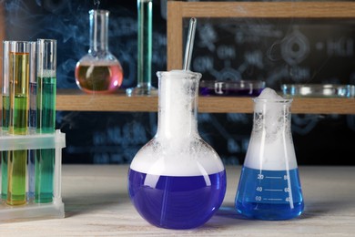 Laboratory glassware with blue liquid on white wooden table. Chemical reaction