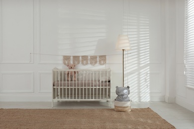 Cute baby room interior with comfortable crib and teddy bear
