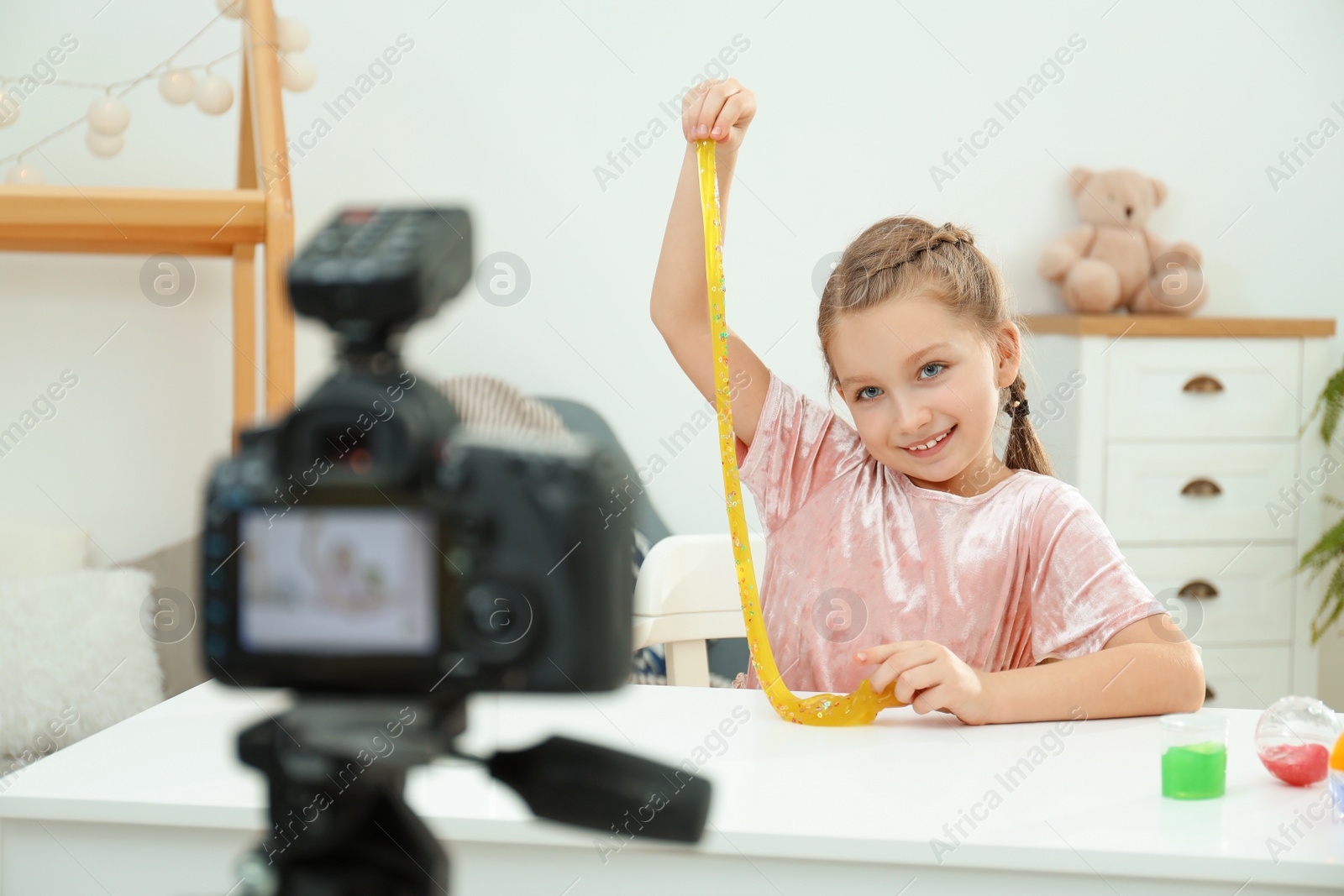 Photo of Cute little blogger with slime recording video at home