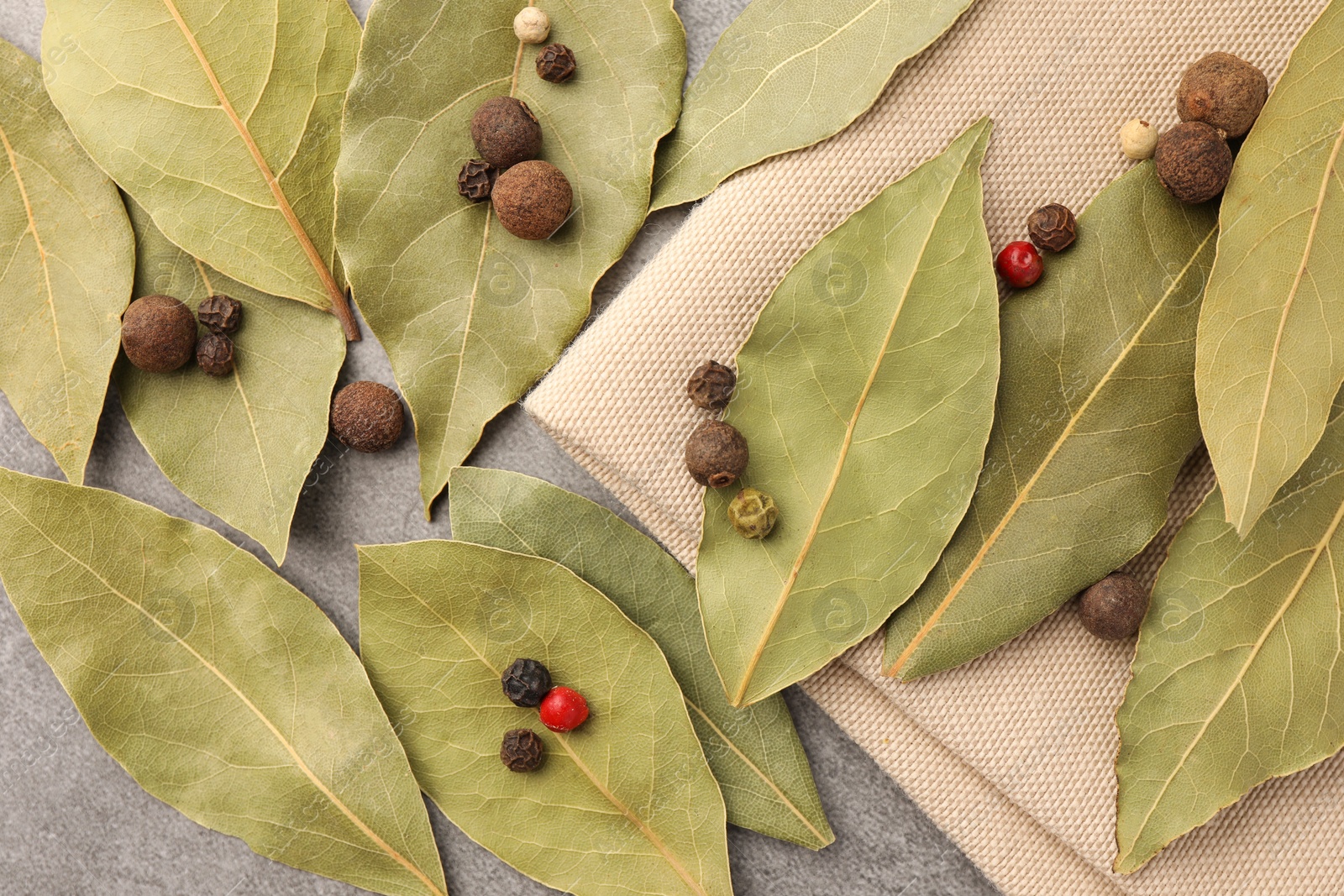 Photo of Aromatic bay leaves and spices on light gray table, flat lay