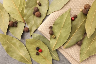 Photo of Aromatic bay leaves and spices on light gray table, flat lay