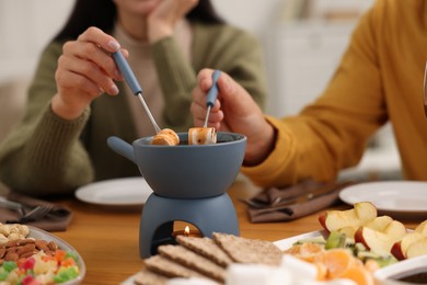 Photo of Couple enjoying chocolate fondue during romantic date indoors, closeup