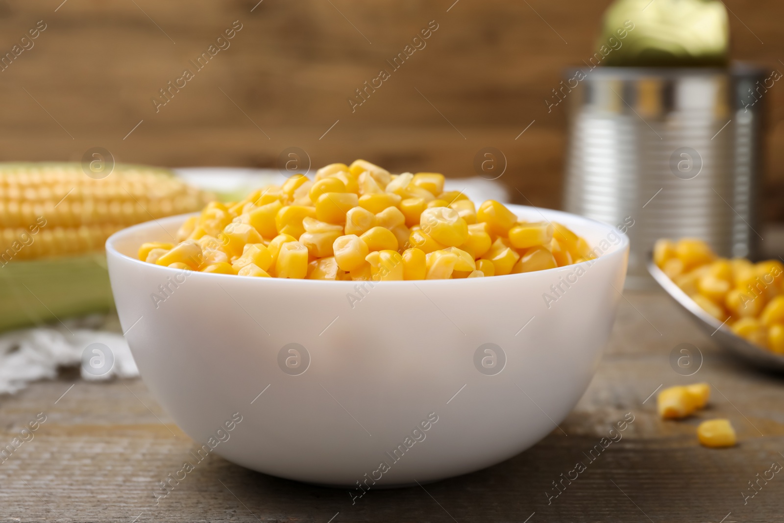 Photo of Bowl of preserved corn on wooden table