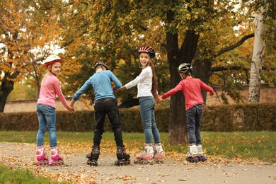 Photo of Cute children roller skating in autumn park