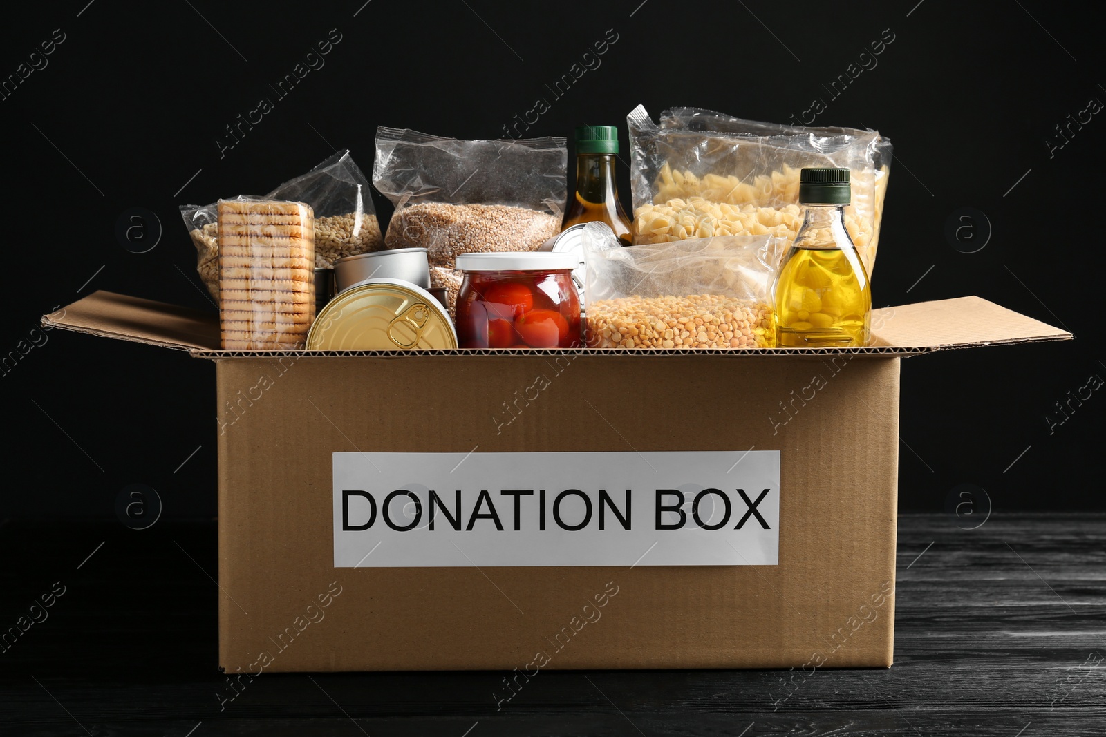 Photo of Donation box with food on black wooden table