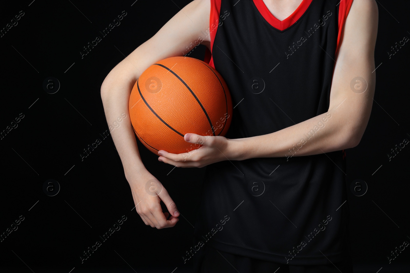 Photo of Boy with basketball ball on black background, closeup