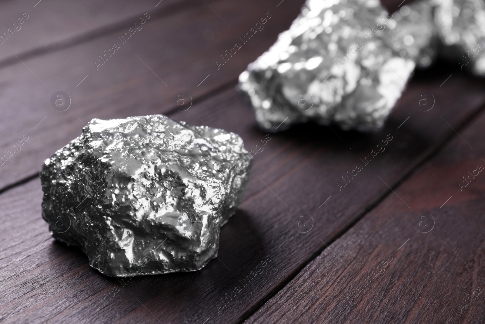 Photo of Silver nuggets on wooden table, closeup. Space for text