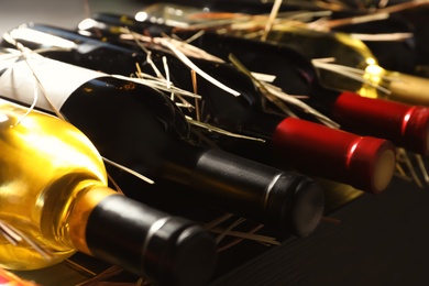 Photo of Bottles with delicious wine on shelf, closeup. Professional sommelier