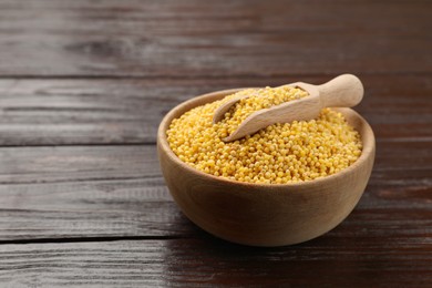 Photo of Millet groats in bowl and scoop on wooden table, space for text