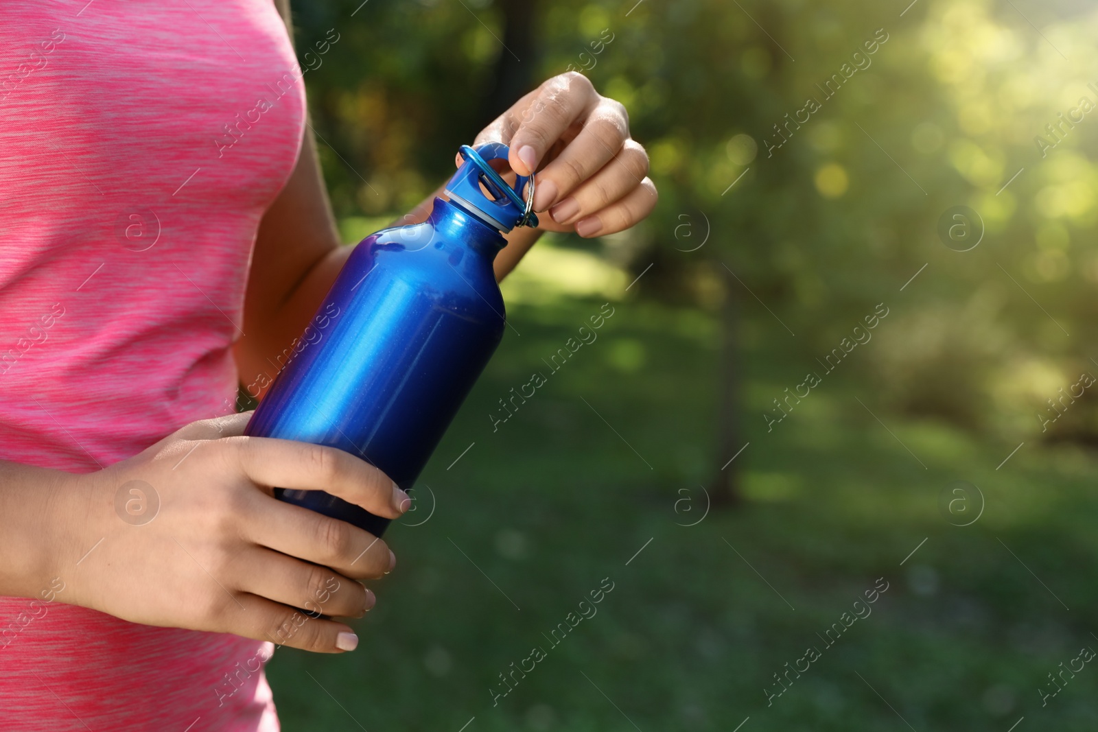 Photo of Young sporty woman with water bottle in park on sunny day, closeup. Space for text