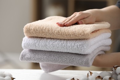 Photo of Woman holding cotton towels over white table in room, closeup