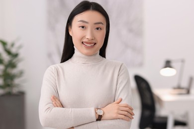 Photo of Portrait of smiling businesswoman with crossed arms in office