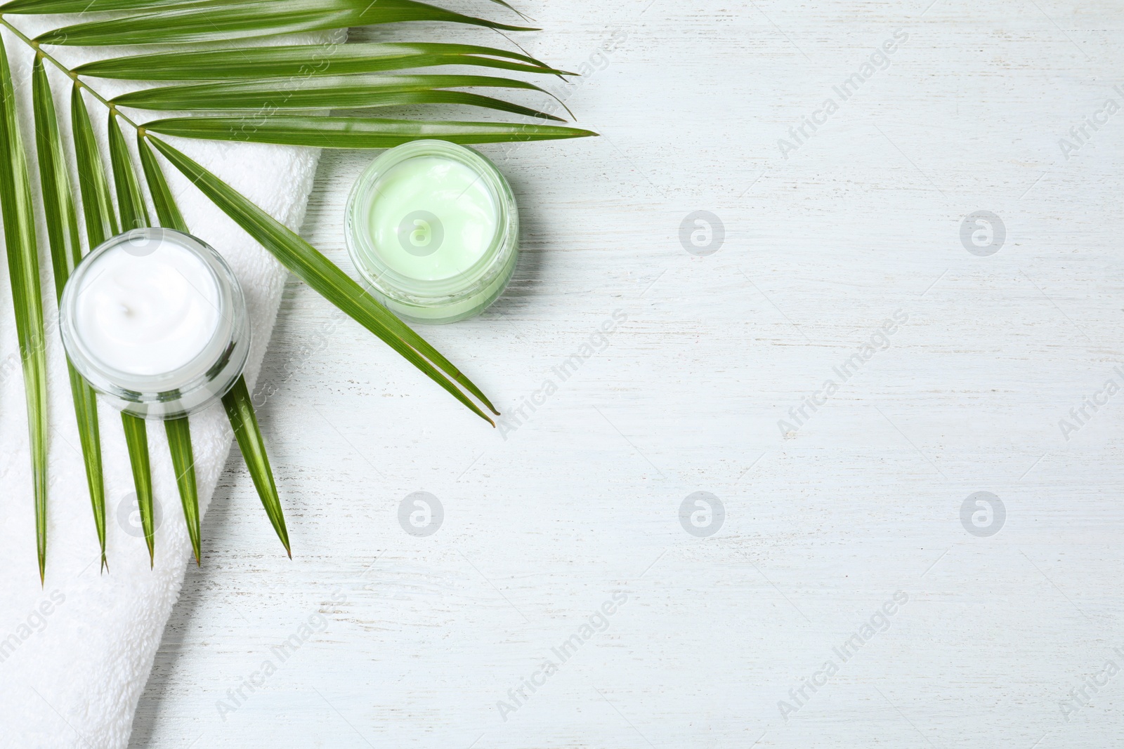 Photo of Flat lay composition with jars of cream on white wooden table. Space for text