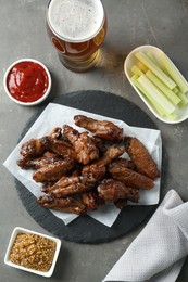 Photo of Delicious chicken wings served with beer on grey table, flat lay