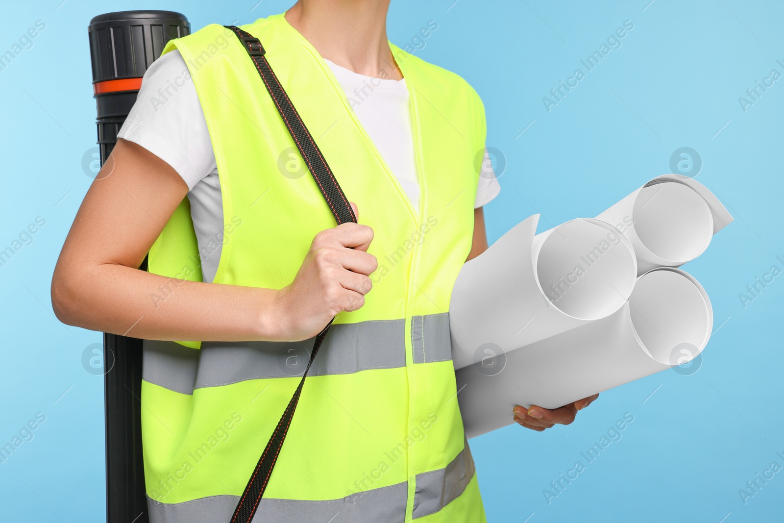 Photo of Architect with drafts and tube on light blue background, closeup