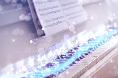 Glowing fairy lights on piano, closeup. Christmas music. Bokeh effect