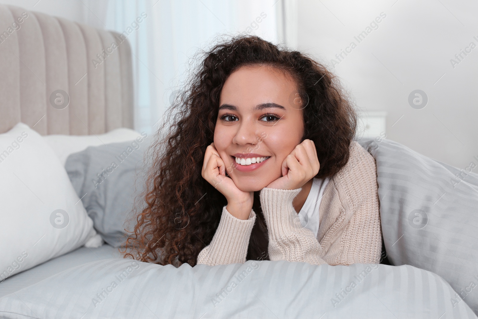 Photo of Happy beautiful African American woman lying in bed at home