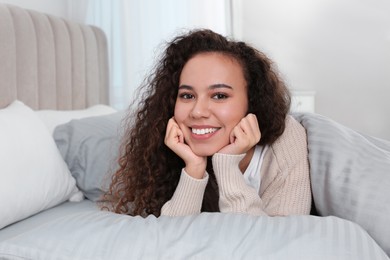 Happy beautiful African American woman lying in bed at home