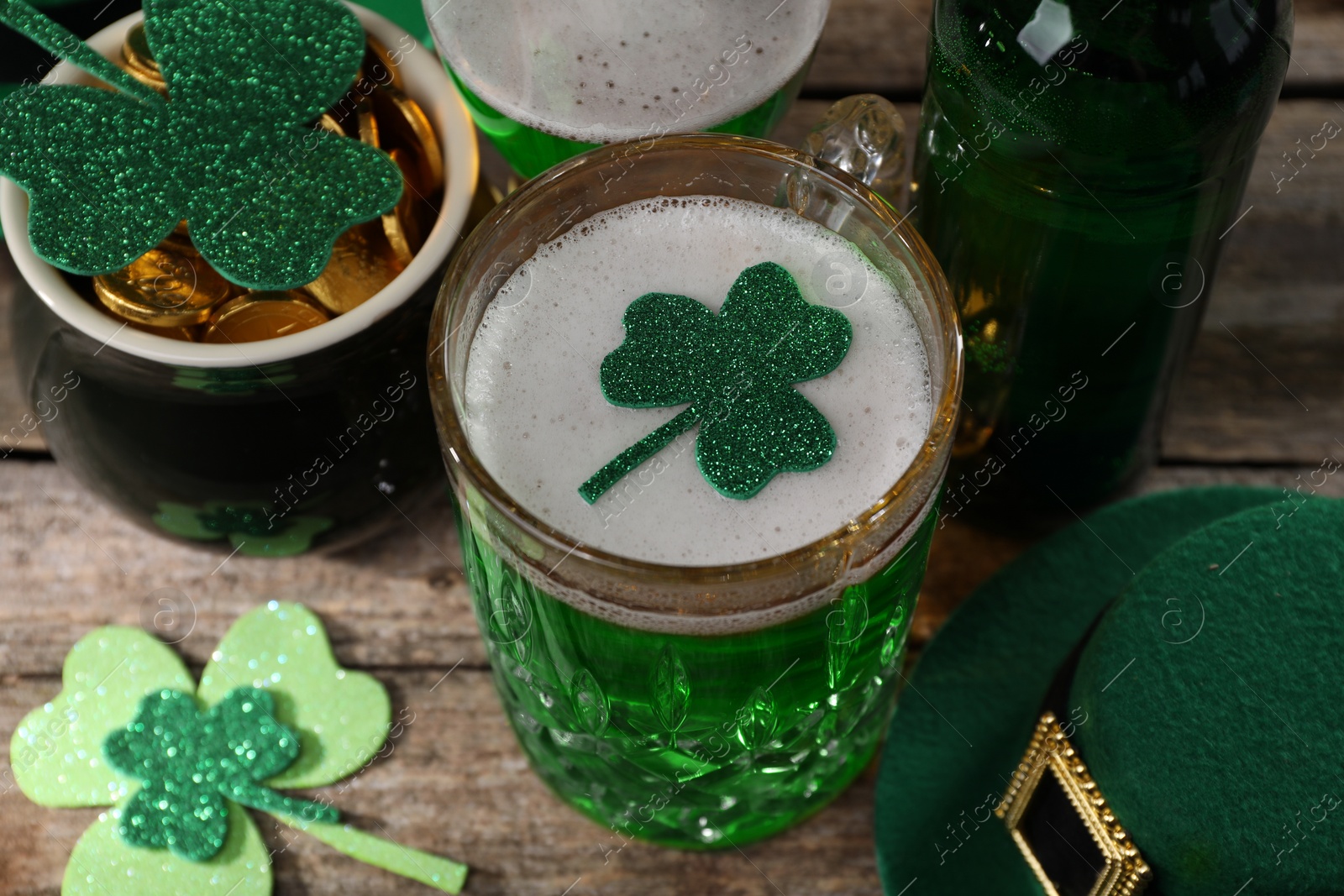 Photo of St. Patrick's day party. Green beer, leprechaun hat, pot of gold and decorative clover leaves on wooden table