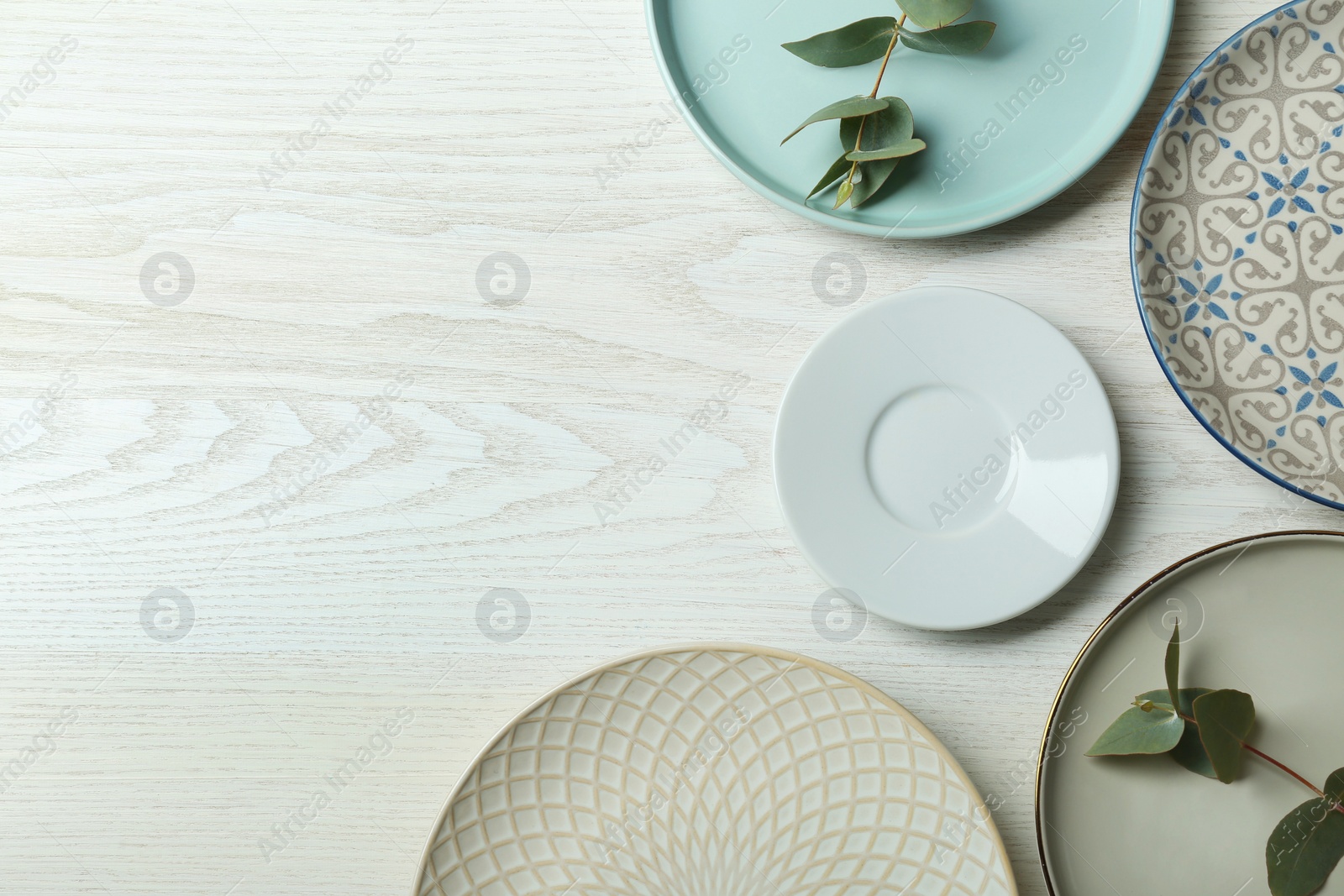 Photo of Flat lay composition with beautiful dishware and green leaves on white wooden table, space for text