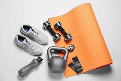Exercise mat and other sport equipment on white background, flat lay