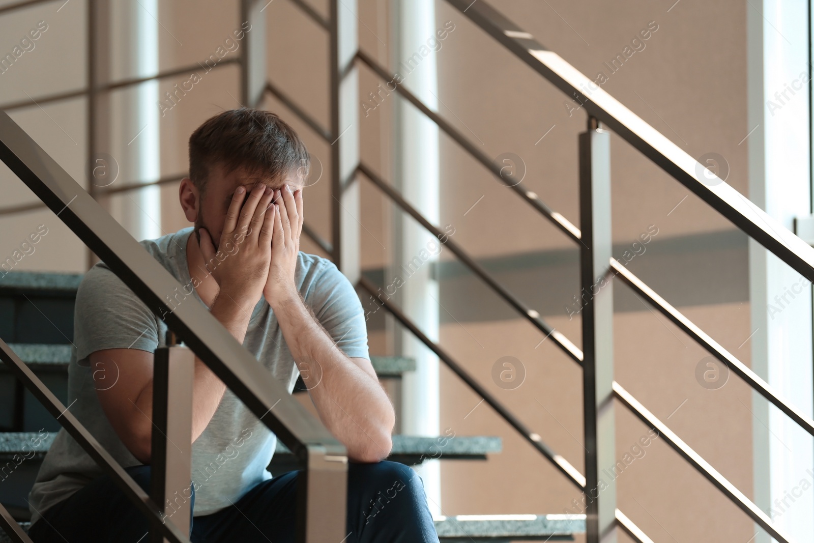 Photo of Depressed young man sitting on stairs