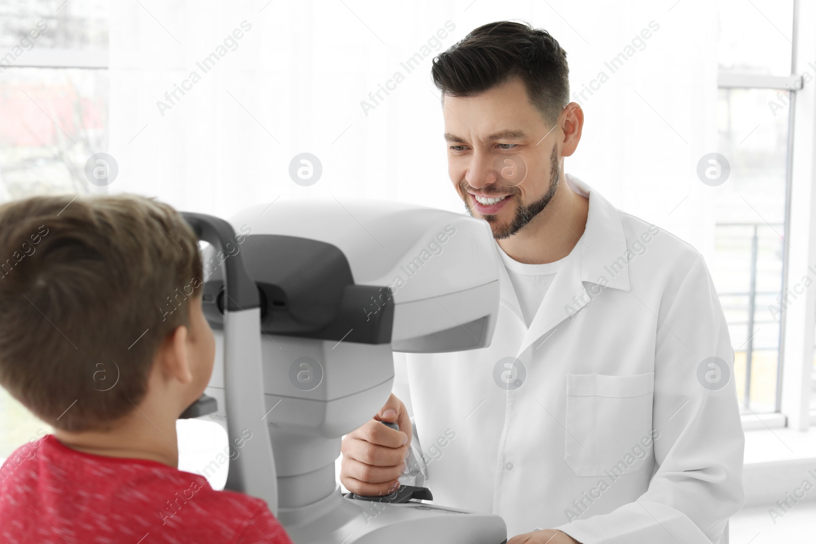 Photo of Ophthalmologist examining little boy in clinic