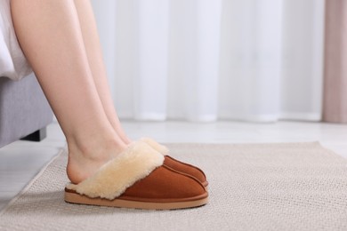 Photo of Woman in brown soft slippers at home, closeup. Space for text