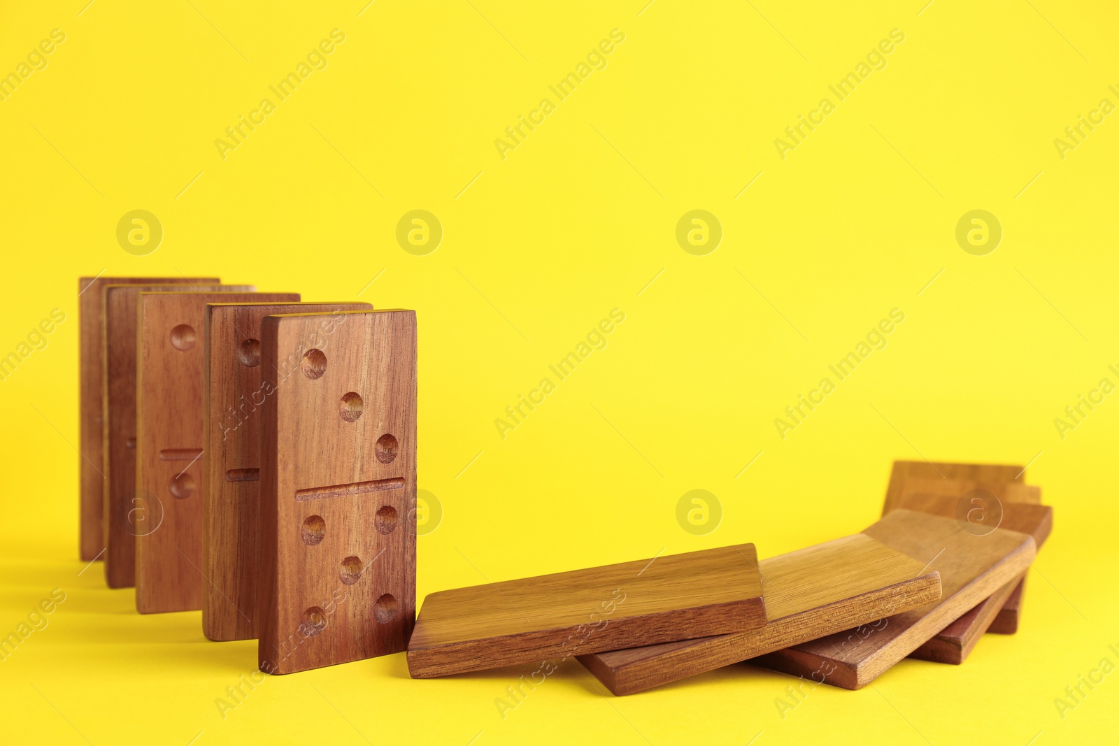 Photo of Falling wooden domino tiles on yellow background