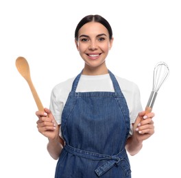 Young woman in blue jeans apron holding wooden spoon and whisk on white background