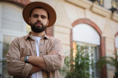 Portrait of handsome bearded man in hat on city street. Space for text